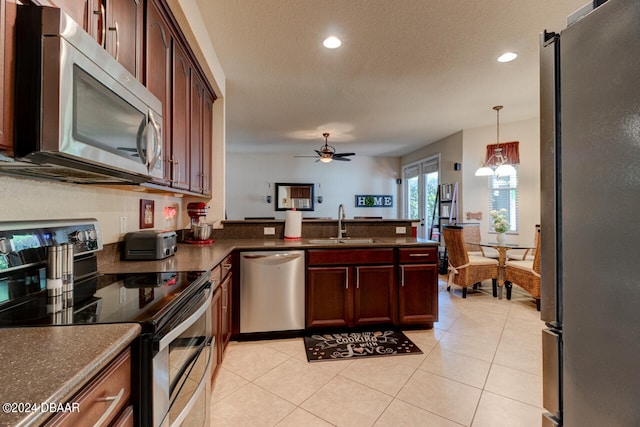 kitchen featuring light tile patterned flooring, stainless steel appliances, decorative light fixtures, sink, and ceiling fan