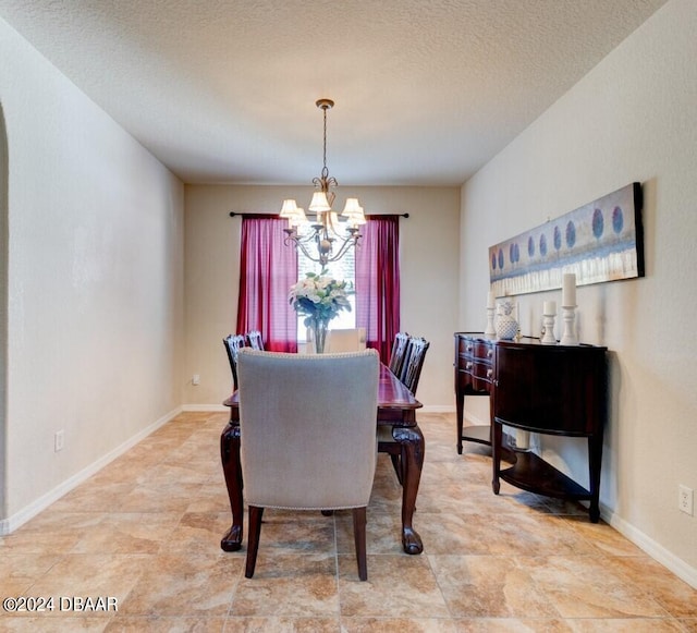 dining area featuring a notable chandelier and a textured ceiling