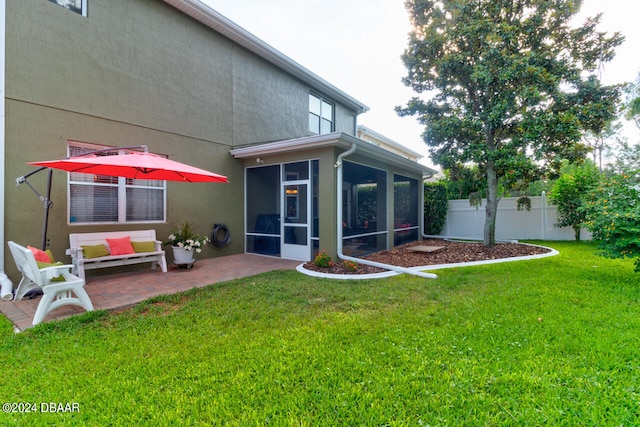 rear view of property with a lawn, a sunroom, and a patio area