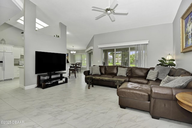 living area with ceiling fan with notable chandelier, high vaulted ceiling, and marble finish floor