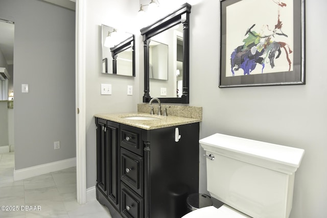 half bathroom with marble finish floor, toilet, vanity, and baseboards