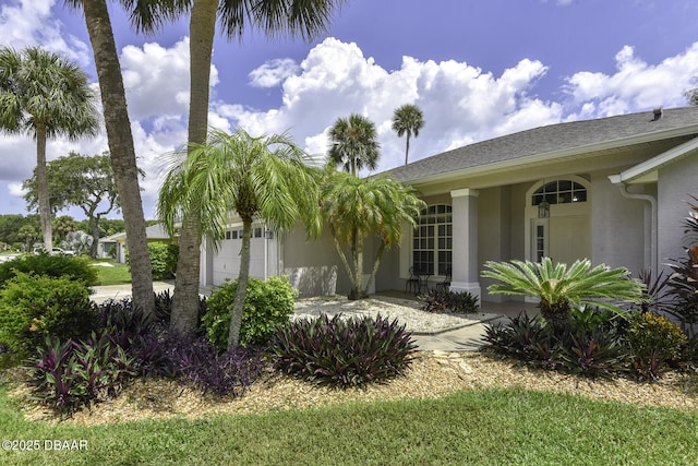 view of side of property with a porch, stucco siding, an attached garage, and driveway