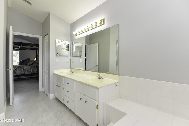 ensuite bathroom featuring a sink, marble finish floor, ensuite bathroom, and vaulted ceiling