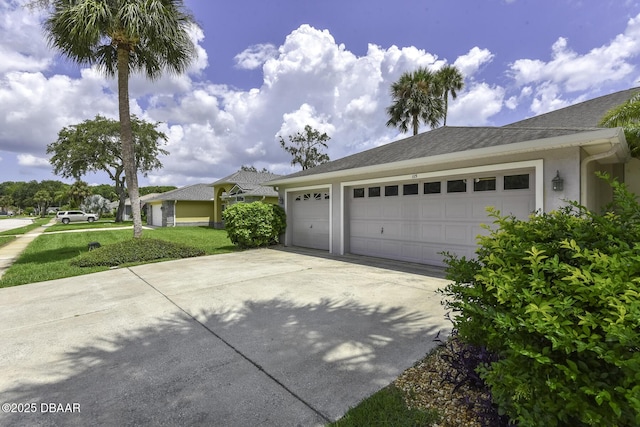 exterior space with an attached garage, a shingled roof, stucco siding, a lawn, and driveway