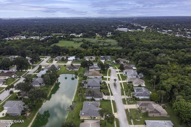 drone / aerial view featuring a view of trees, a water view, and a residential view