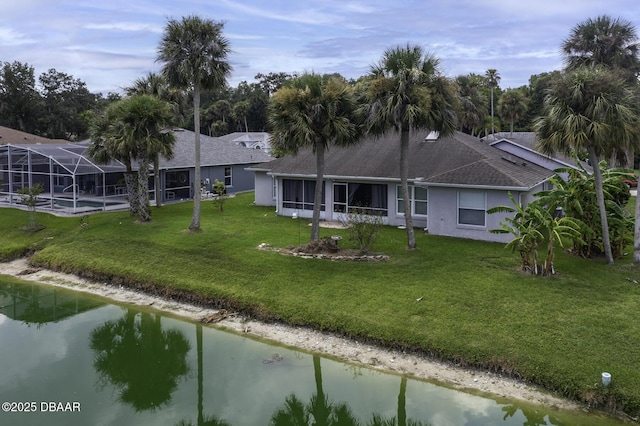 back of property featuring stucco siding, a water view, a lawn, and a lanai