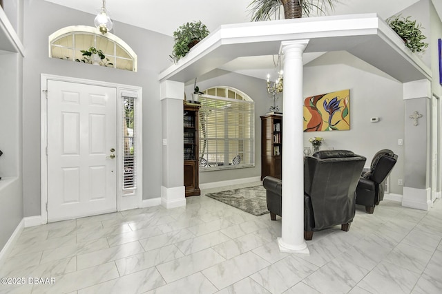 foyer entrance featuring baseboards, lofted ceiling, marble finish floor, and ornate columns