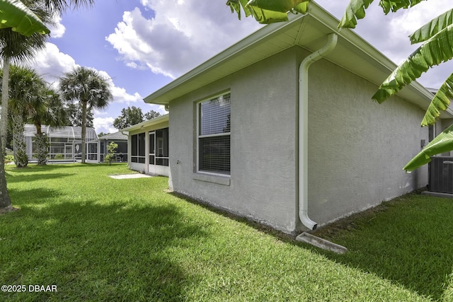 view of home's exterior featuring stucco siding, a yard, and a sunroom