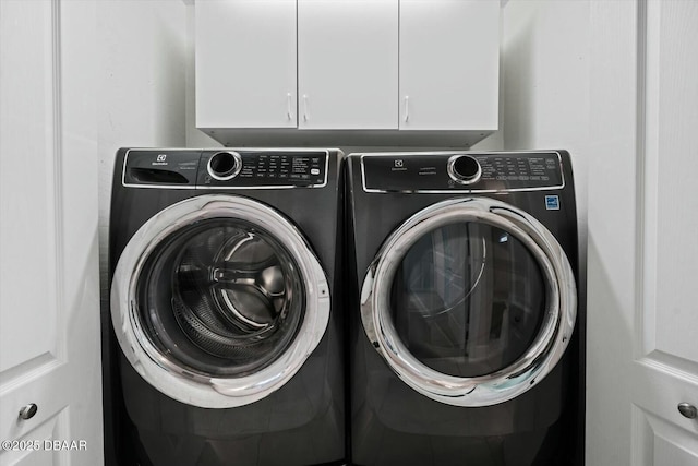 laundry area featuring washer and clothes dryer and cabinets