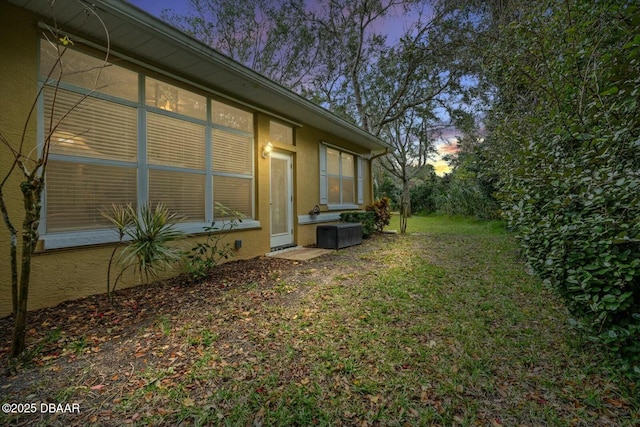 property exterior at dusk featuring a lawn