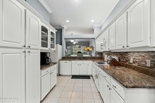 kitchen featuring dark stone countertops, white cabinets, light tile patterned flooring, and white appliances