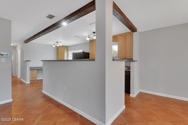 kitchen with beam ceiling, plenty of natural light, black appliances, and light tile patterned floors