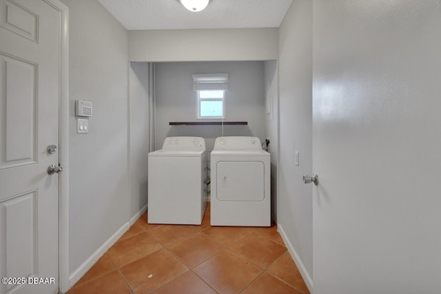 clothes washing area featuring light tile patterned floors, baseboards, a textured ceiling, and independent washer and dryer