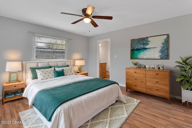 bedroom with a ceiling fan, baseboards, ensuite bath, and wood finished floors