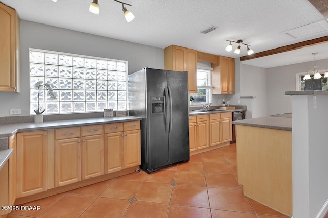 kitchen with light tile patterned floors, visible vents, a sink, a textured ceiling, and black fridge