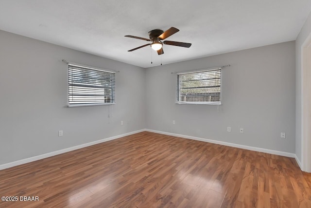 spare room featuring a wealth of natural light, baseboards, and wood finished floors