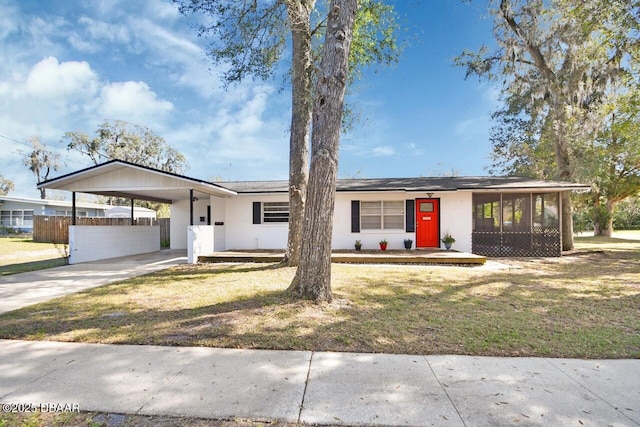 view of front of property featuring an attached carport, a sunroom, driveway, and a front yard