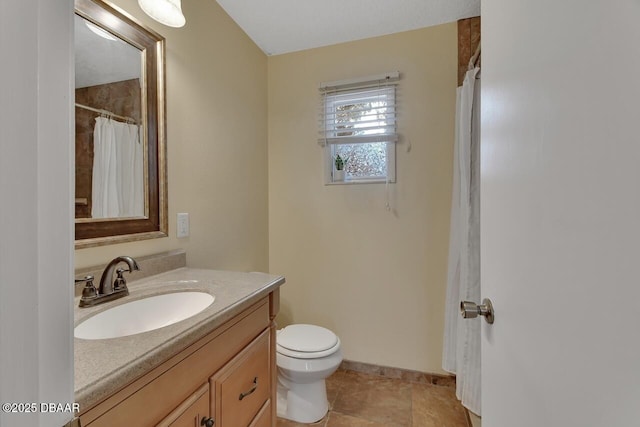 bathroom with tile patterned flooring, baseboards, vanity, and toilet