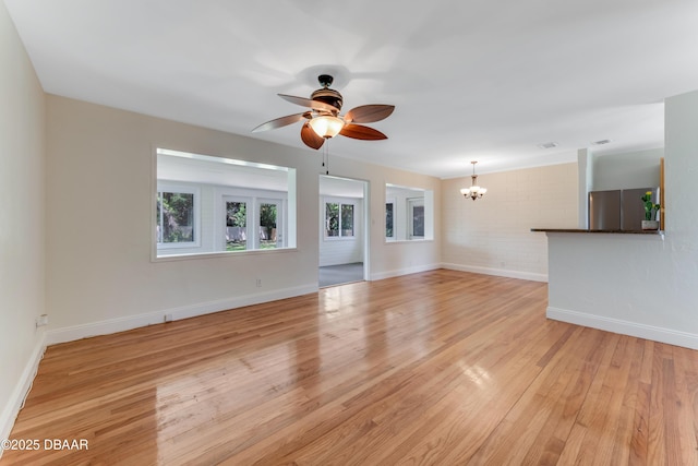 556 N Beach St, Ormond Beach, FL 32174 - unfurnished living room with a chandelier, a ceiling fan, light wood finished floors, and baseboards