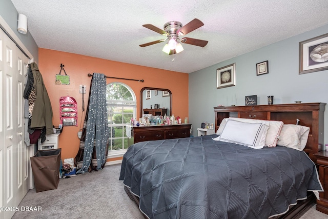 carpeted bedroom with a textured ceiling, a closet, and ceiling fan