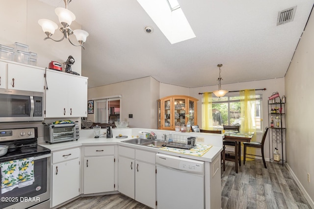 kitchen with pendant lighting, white cabinets, a skylight, appliances with stainless steel finishes, and kitchen peninsula