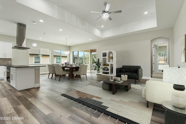 living room featuring hardwood / wood-style floors, a raised ceiling, and ceiling fan