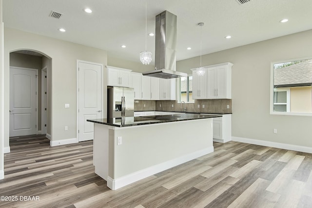 kitchen featuring stainless steel refrigerator with ice dispenser, island range hood, a center island, pendant lighting, and white cabinets