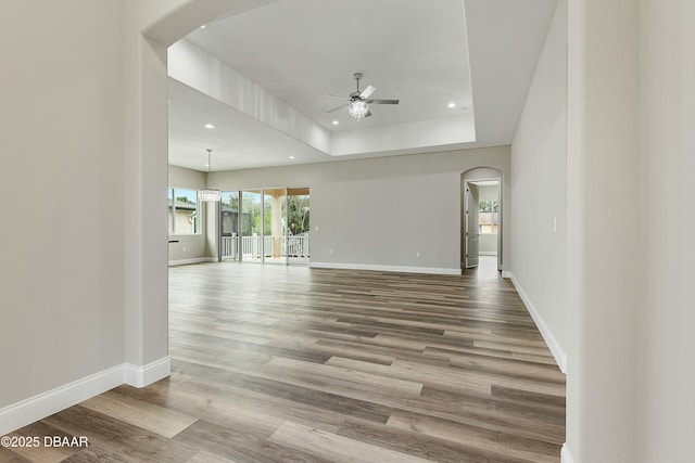 empty room featuring a raised ceiling, hardwood / wood-style flooring, and ceiling fan