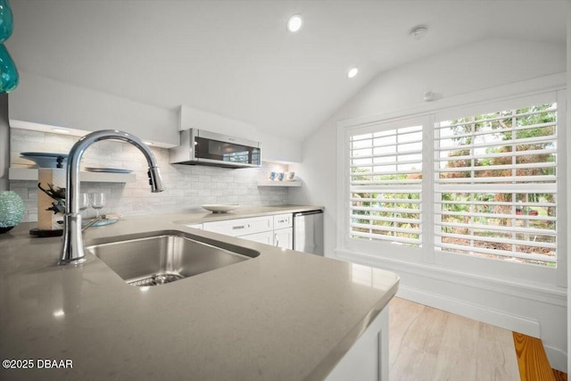 96 Grove St, Ormond Beach, FL 32174 - kitchen with stainless steel appliances, a sink, white cabinetry, backsplash, and lofted ceiling