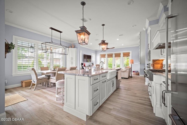 96 Grove St, Ormond Beach, FL 32174 - kitchen featuring a sink, white cabinetry, ornamental molding, a kitchen breakfast bar, and light wood finished floors