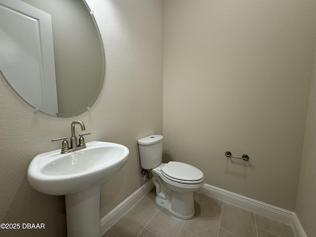 half bath featuring tile patterned floors, baseboards, and toilet