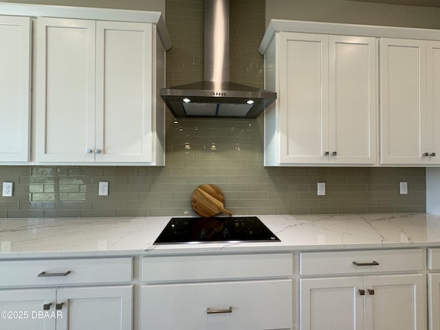 kitchen featuring black electric stovetop, tasteful backsplash, white cabinets, and wall chimney range hood