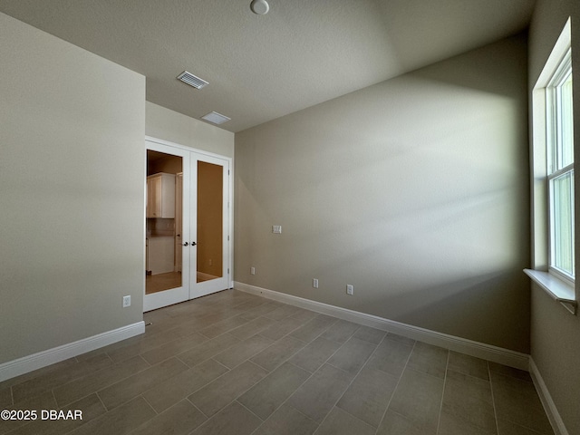 empty room with french doors, visible vents, and baseboards