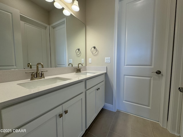 bathroom with tile patterned floors, double vanity, baseboards, and a sink