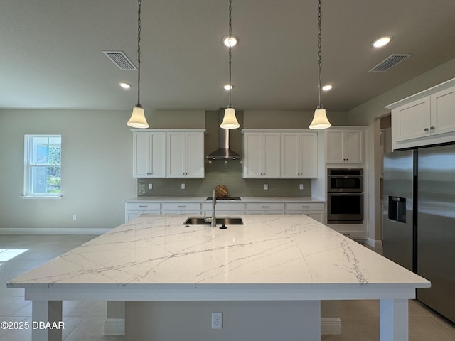 kitchen with visible vents, wall chimney range hood, decorative backsplash, stainless steel appliances, and a sink