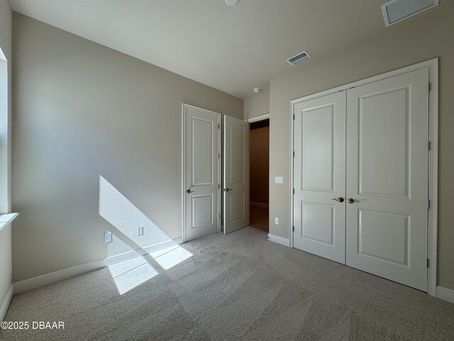 unfurnished bedroom featuring a closet, baseboards, visible vents, and carpet floors