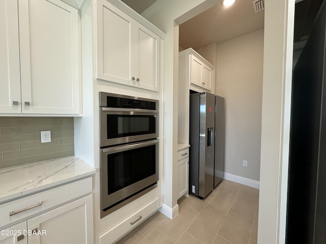 kitchen with light stone counters, visible vents, stainless steel appliances, white cabinetry, and tasteful backsplash