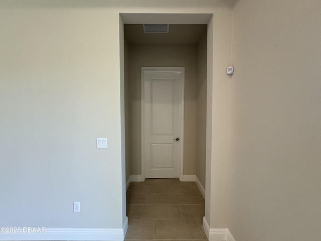 corridor with visible vents, baseboards, and tile patterned flooring