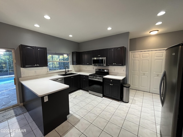 kitchen featuring sink, tasteful backsplash, light tile patterned flooring, kitchen peninsula, and stainless steel appliances