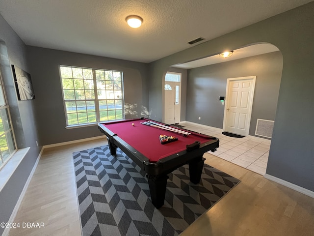 game room featuring light wood-type flooring, a textured ceiling, and billiards