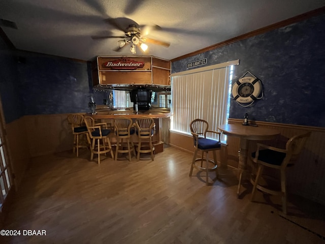 dining room featuring hardwood / wood-style floors, ceiling fan, crown molding, and a textured ceiling