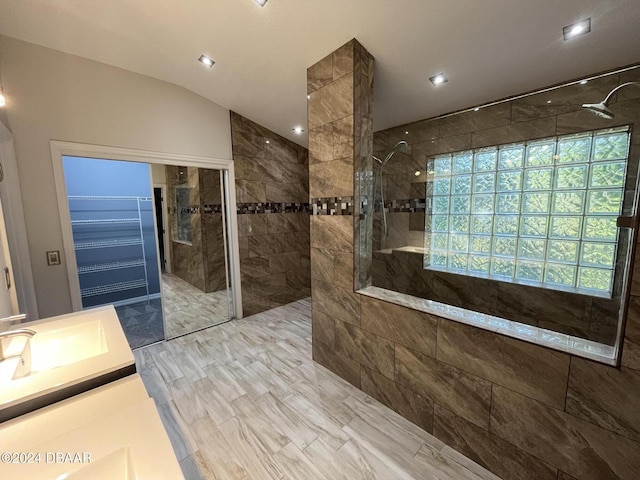 bathroom with a tile shower, vanity, and lofted ceiling