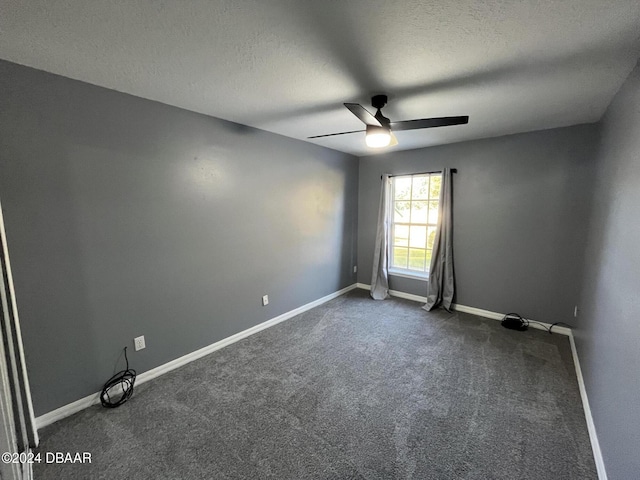 empty room featuring ceiling fan, dark carpet, and a textured ceiling