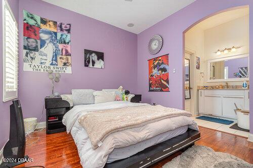 bedroom with wood-type flooring, ensuite bath, and multiple windows