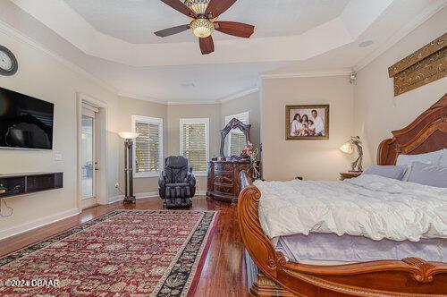 bedroom with a tray ceiling, ceiling fan, dark hardwood / wood-style flooring, and ornamental molding