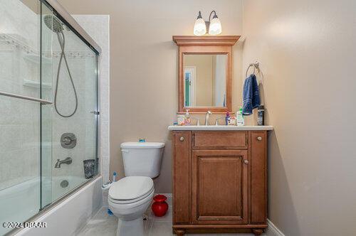 full bathroom featuring tile patterned floors, vanity, toilet, and combined bath / shower with glass door