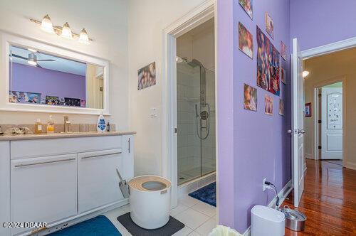 bathroom with vanity, hardwood / wood-style flooring, walk in shower, and ceiling fan