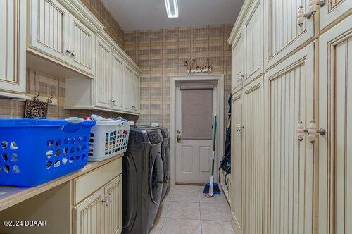 washroom featuring washer and dryer, cabinets, and light tile patterned floors