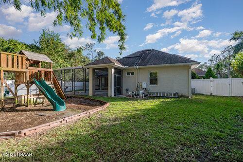 rear view of house featuring a playground and a lawn