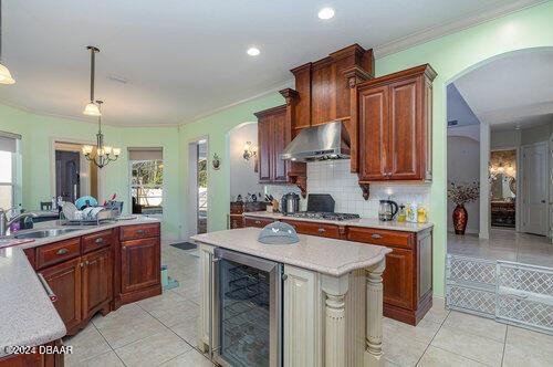 kitchen with beverage cooler, sink, light tile patterned floors, a chandelier, and hanging light fixtures